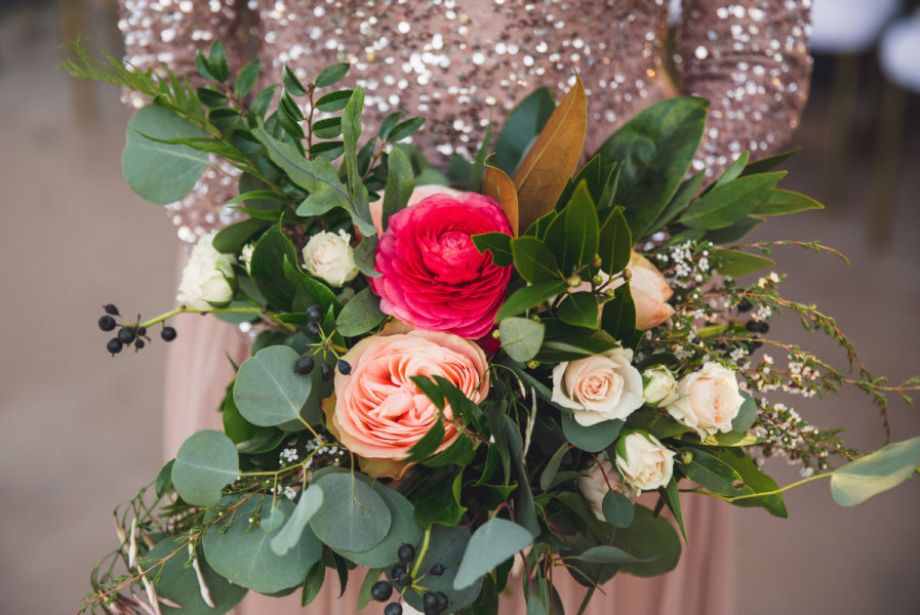 Close-up of a colorful wedding bouquet with blush and fuchsia roses, greenery, and berries at Villa Antonia