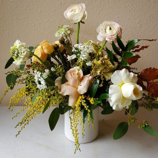 Ava floral arrangement in a white vase with blush and white blooms, yellow accents, and lush greenery
