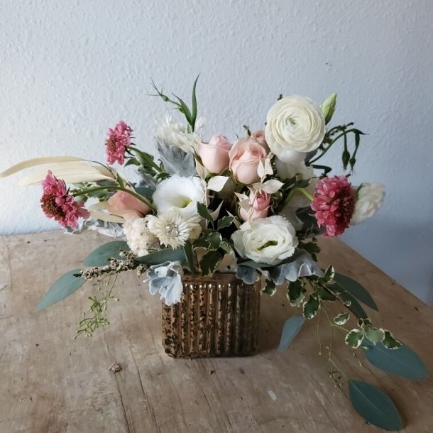 Reverie floral arrangement with blush roses, white ranunculus, and pink blooms in a ribbed glass vase