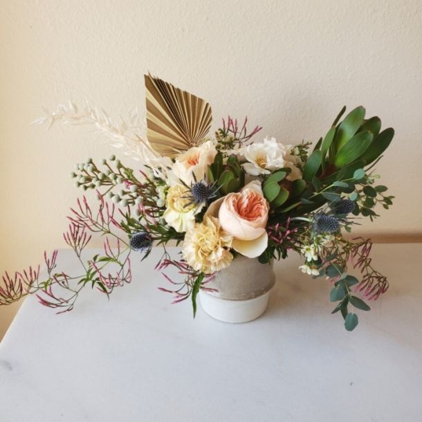 Boho Vibe floral arrangement with blush roses, white blooms, eucalyptus, and dried palm in a ceramic vase