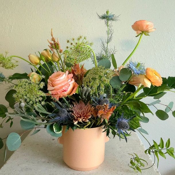 Sasha floral arrangement in a blush ceramic pot with peach blooms, blue thistle, greenery, and eucalyptus